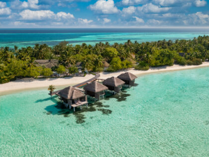 Aerial view of Maldives island, luxury water villas resort and wooden pier. Beautiful sky
