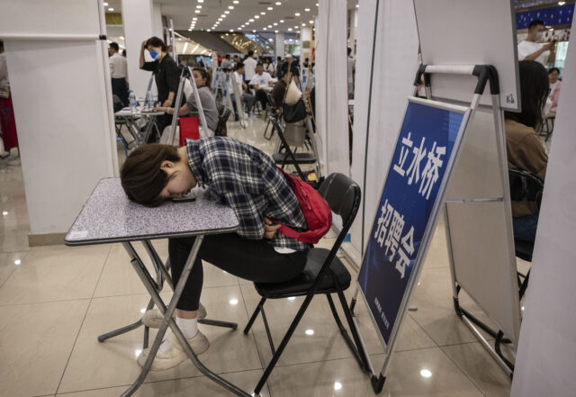 BEIJING, CHINA - JUNE 9: A woman rests on a table at a job fair on June 9, 2023 in Beijing