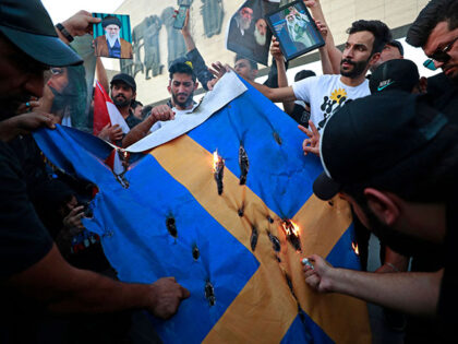 Supporters of the former paramilitary group Hashd al-Shaabi burn a Swedish flag during a p