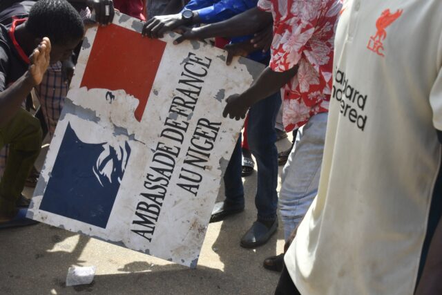 TOPSHOT - Protesters hold a sign taken from the French Embassy in Niamey during a demonstr