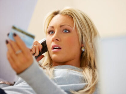 Stressed woman looking at bills and talking on phone at home