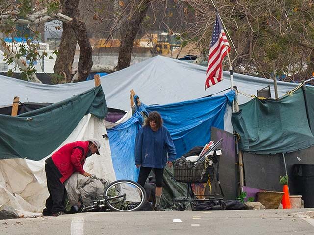 A homeless encampment made of tents and tarps lines the Santa Ana riverbed near Angel Stad