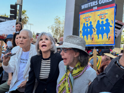 Hollywood, CA - June 29: Actress and activist Jane Fonda, center in dark jacket, and her "9 to 5" co-star Lily Tomlin, right, joined by the 1980 film's screenwriter Patricia Resnick, left in white jacket, cheer during a "Striking 9 to 5" picket line in front of Netflix headquarters, in …