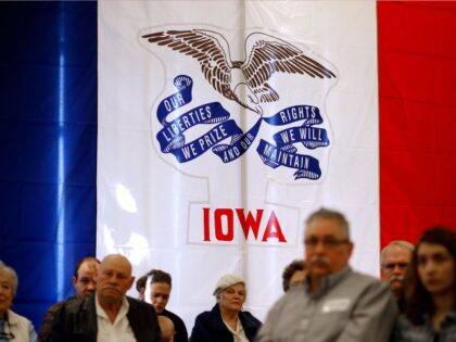 The Iowa state flag stands behind attendees as they listen to Republican presidential cand