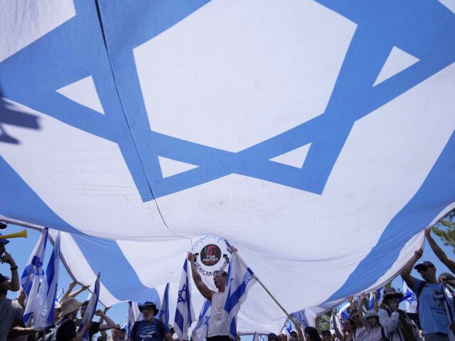 Demonstrators wave a large Israeli flag during a protest against plans by Prime Minister B