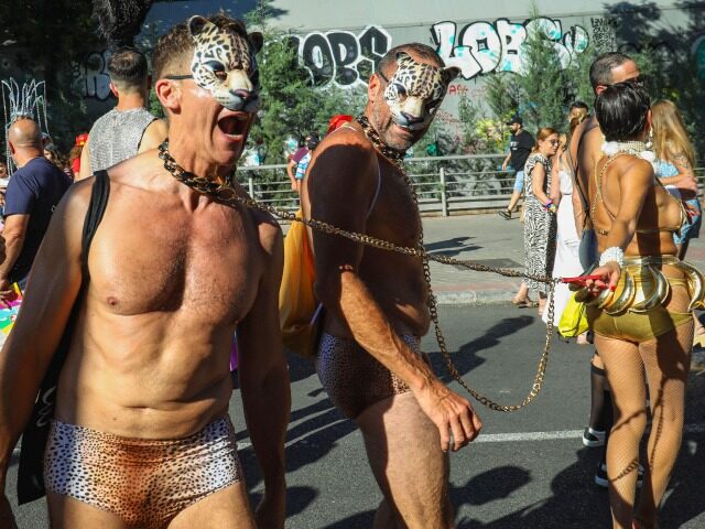 MADRID, SPAIN - 2023/07/01: A couple of masked men are pulled in chains by a woman during