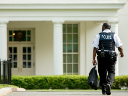 A uniformed Secret Service agent walks towards the entrance of the West Wing of the White