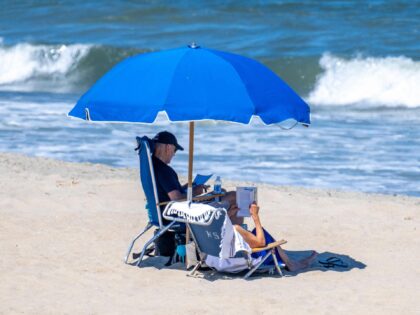 TOPSHOT - US President Joe Biden (L) and US First Lady Jill Biden sit under an umbrella in