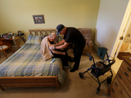 In this Nov. 27, 2013 photo, caregiver Warren Manchess washes Paul Gregoline, in Noblesville, Ind. Gregoline, 92, and battling Alzheimer's, needs a hand with nearly every task the day brings. Burgeoning demand for senior services like home health aides is being met by a surprising segment of the workforce: Other …