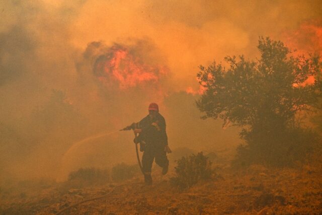 A firefighter tries to control a blaze in New Peramos, near Athens on July 19