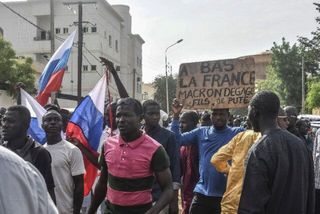 Junta supporters, some holding anti-French slogans and some waving Russian flags, gathered