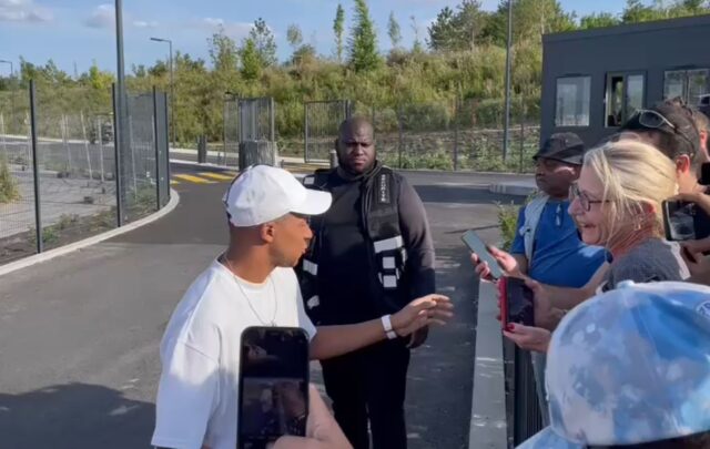 Kylian Mbappe (L) stops to greet fans at PSG's training grounds in Poissy, outside Paris,