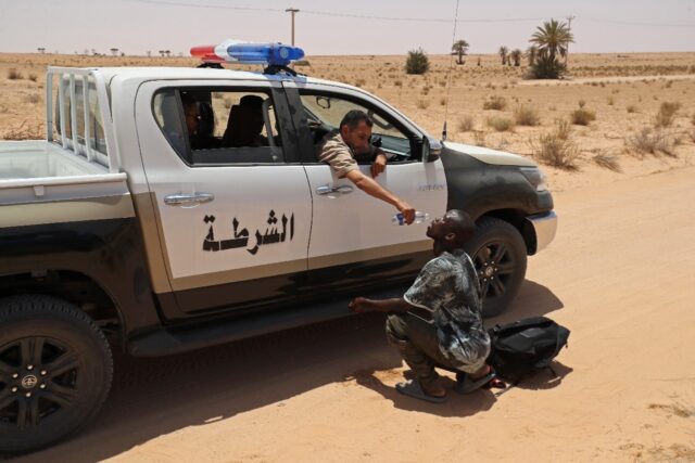 A Libyan border guard gives water to a migrant during a rescue operation in an uninhabited