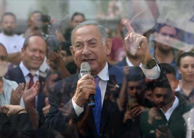 Netanyahu speaks to university students from behind a security screen during a campaign ra