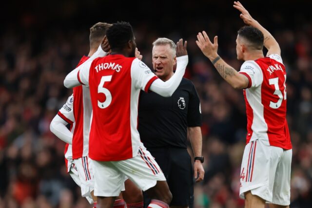 Referee Jonathan Moss (C) is surrounded by Arsenal players