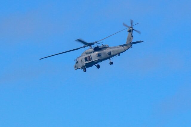 A Royal Australian Navy helicopter conducts search and rescue operations for the crashed c