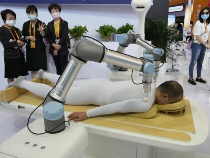 Visitors look at robot arms performing acupressure massage at a booth during China International Fair for Trade in Services (CIFTIS) in Beijing, Friday, Sept. 2, 2022. (Ng Han Guan/AP)