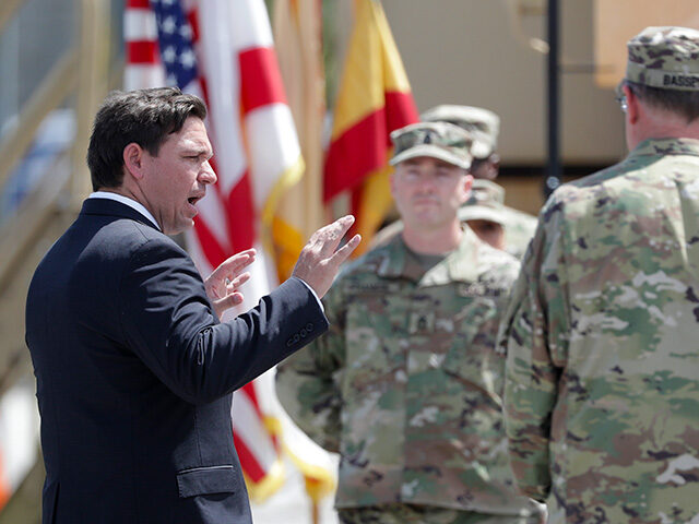 Florida Gov. Ron DeSantis, left, talks with members of the Florida National Guard, Sunday,