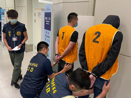 In this photo released by the Taiwan Criminal Investigation Bureau, police officers from the Taiwan Criminal Investigation Bureau search the bodies of two suspect who were deported from Bangkok and believed to be involved in scam cases in Cambodia as they arrive back at the Taoyuan International Airport in Taiwan …