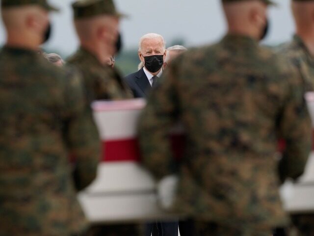 President Joe Biden watches as a carry team moves a transfer case containing the remains o