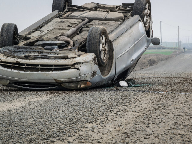 An overturned car on a rural road. - stock photo