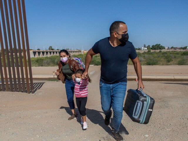 YUMA, AZ - MAY 13: A family of asylum seekers from Cuba cross an open section of wall at t
