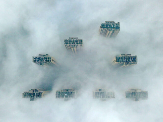 TOPSHOT - This aerial view shows the tops of highrise buildings poking out from heavy fog