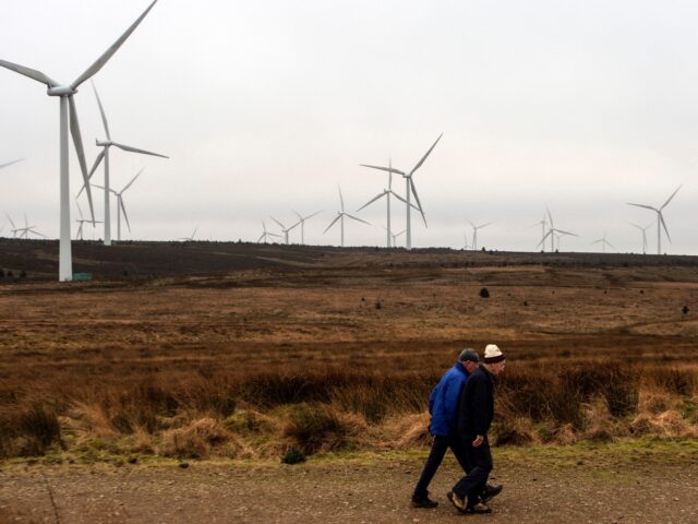 Members of the public walk past wind turbines operated by ScottishPower Renewables, at Whitelee Onshore Windfarm on Eaglesham Moor, southwest of Glasgow, on January 17, 2022. - Whitelee, operated by Scottish Power, is the UK's largest onshore wind farm - its 215 turbines are said to be able to generate …