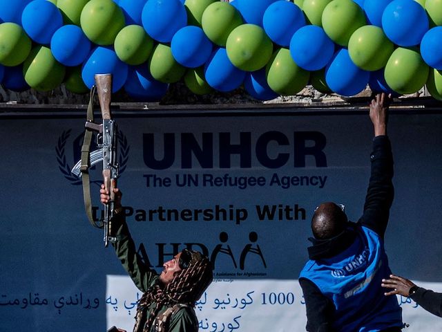 In this photo taken on December 15, 2022, a member of Taliban security adjust balloons with his gun during a handover ceremony of newly built houses constructed by the United Nations refugee agency (UNHCR) in Barmal district, Paktika province. - More than 1,000 people were killed and tens of thousands made homeless after the 5.9-magnitude quake -- the deadliest in Afghanistan in nearly a quarter of a century -- struck the impoverished province of Paktika on June 22. - To go with AFP story Afghanistan-earthquake (Photo by Wakil KOHSAR / AFP) / To go with AFP story Afghanistan-earthquake (Photo by WAKIL KOHSAR/AFP via Getty Images)