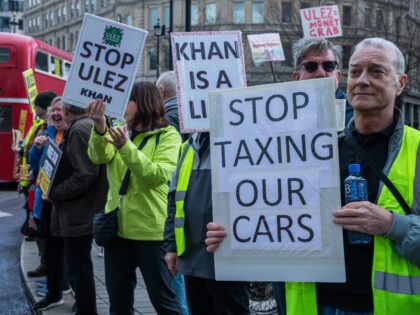 Protesters against the expansion of London's Ultra-Low Emission Zone (ULEZ) stand holding