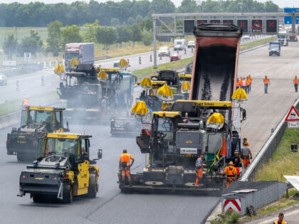 16 June 2023, Bavaria, Munich: Workers use large road construction machines to place fresh whispering asphalt on the A9 autobahn in the north of the Bavarian capital. According to the operator, around five to six meters of roadway are completed every minute. Photo: Peter Kneffel/dpa (Photo by Peter Kneffel/picture alliance …