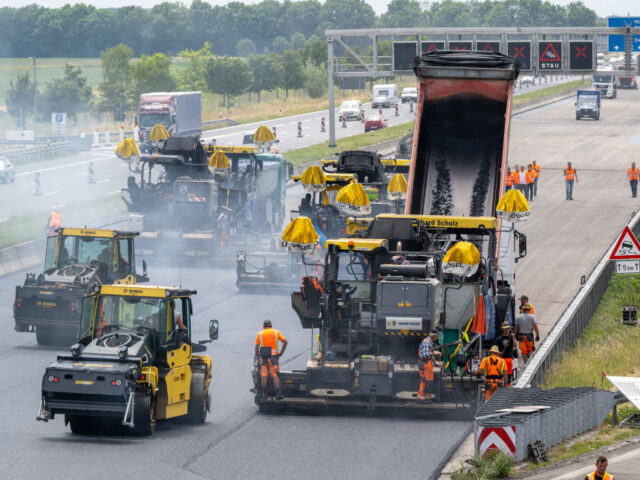 16 June 2023, Bavaria, Munich: Workers use large road construction machines to place fresh