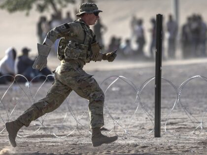 EL PASO, TEXAS - MAY 10: A Texas National Guard soldier runs while setting up razor wire a