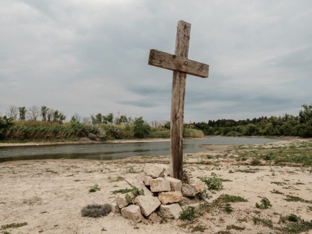 VELYKA OLEKSANDRIVKA, UKRAINE - JULY 13: A wooden cross is installed on the shore of Inhulets River on July 13, 2023 in Velyka Oleksandrivka Village, Kherson Oblast, Ukraine. Velyka Oleksandrivka, an urban-type settlement in southern Ukraine, was occupied by the Russian troops on March 10, 2022 and liberated by Ukrainian …