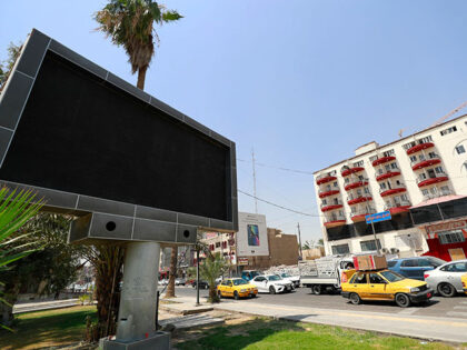 Vehicles drive past a shut advertisement screen at the Uqba Bin Nafia square in Baghdad on