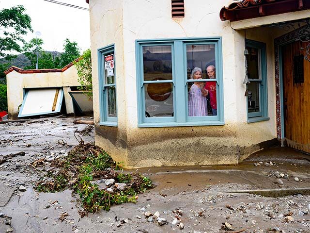 Residents trapped in their home peer out a window while waiting for help in Yucaipa, Calif
