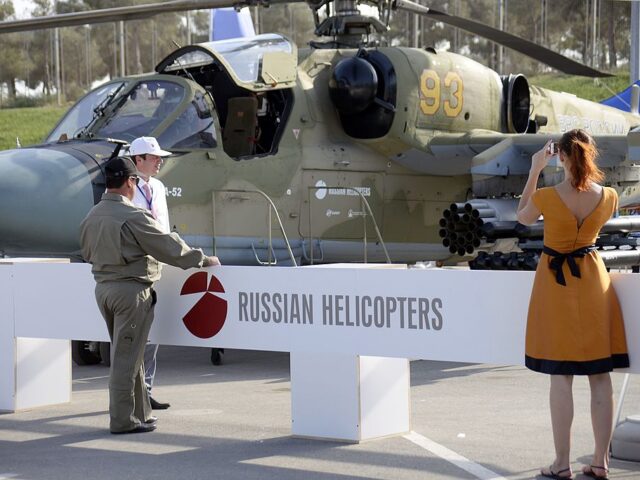 A woman as she takes a photo of a Russian military helicopter KA-52 at the ADEX 2014 Inter
