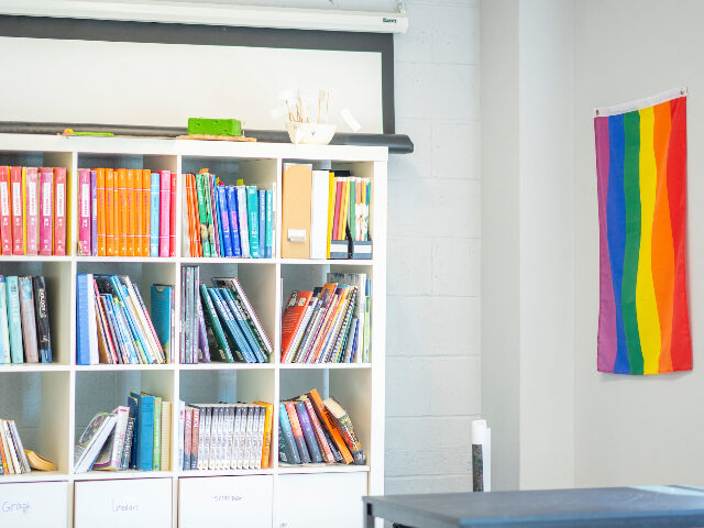 A teachers corner of a Montessori classroom with bookshelves containing binders and textbo
