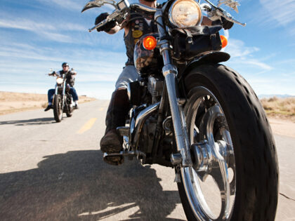 Two men riding motorcycles along road - stock photo