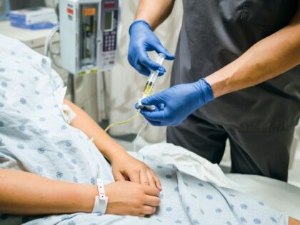Nurse injecting medicine into tube of patient - stock photo