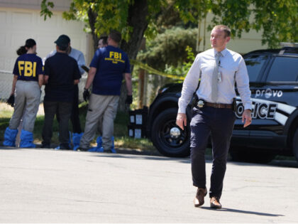 PROVO, UTAH - AUGUST 9: A Provo police officer walks away as FBI officials and other law enforcement officers stand outside the home of Craig Robertson who was shot and killed by the FBI in a raid on his home this morning on August 9, 2023 in Provo, Utah. The …