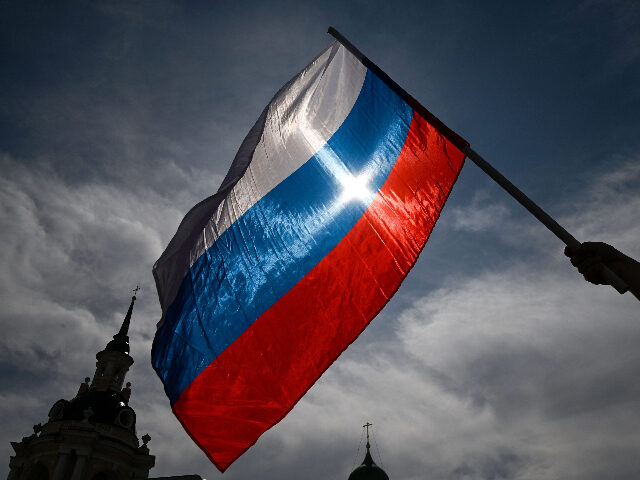 TOPSHOT - A man waves the Russian national flag as he arrives at the patriotic concert at
