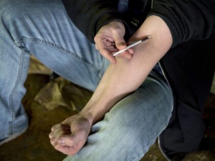 In this June 13, 2017, file photo, a man injects heroin into this arm under a bridge along the Wishkah River at Kurt Cobain Memorial Park in Aberdeen, Wash. The government said non-fatal overdoses visits to hospital emergency rooms were up about 30 percent late last summer, compared to the …