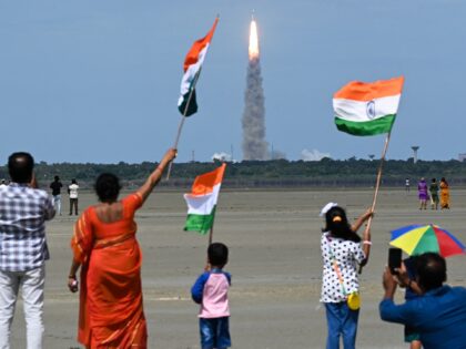 People wave Indian flags as an Indian Space Research Organisation (ISRO) rocket carrying the Chandrayaan-3 spacecraft lifts off from the Satish Dhawan Space Centre in Sriharikota, an island off the coast of southern Andhra Pradesh state on July 14, 2023. India launched a rocket on July 14 carrying an unmanned …