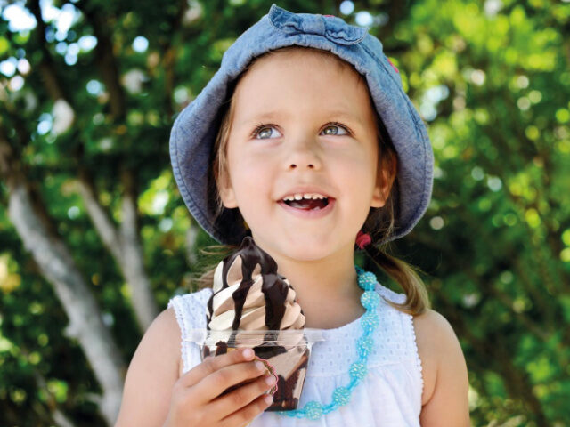 A little girl holds a Soft Serve On the Go ice cream cup.