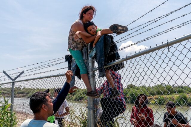 Ecuadoran migrant Nataly Barrionuevo, holding one of her sons in her arms, crosses a barbe