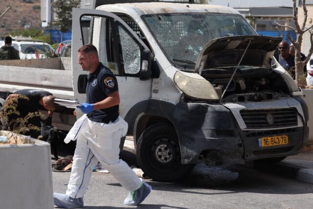 Israeli forensic officers inspect a bullet-riddled truck next to a checkpoint outside the