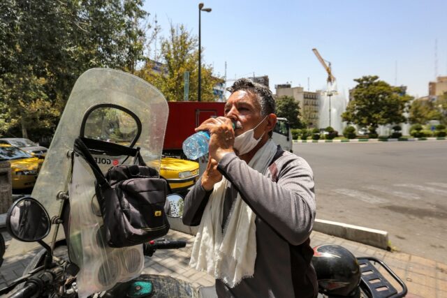 A motorcyclist takes a break in the heat of Tehran on July 11, 2023