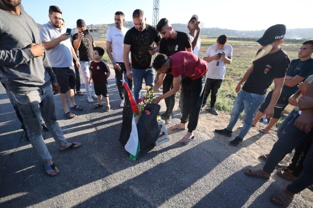Mourners lay roses at the site where three Palestinians were killed by Israeli forces near