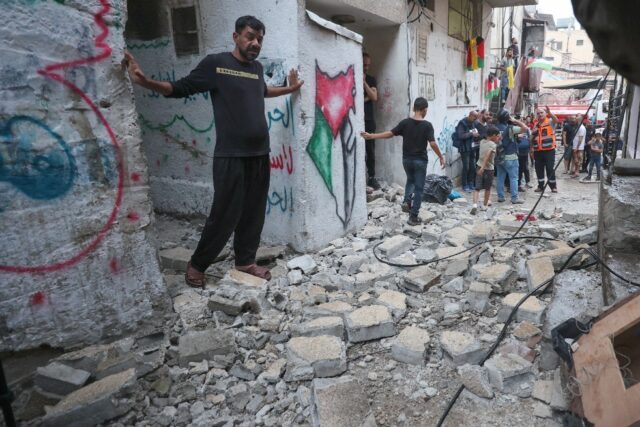 Palestinian emergency personnel and residents inspect the damage following the Israeli rai